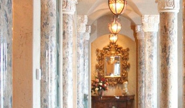 A hallway with marble columns and a chandelier.