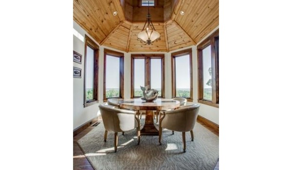 A dining room with large windows and a wooden ceiling.