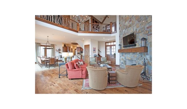 A large living room with wood floors and a stone fireplace.